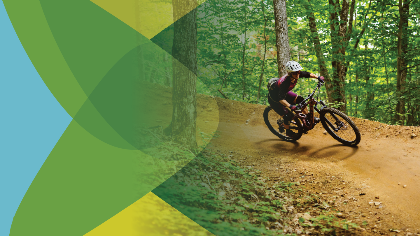 Une cycliste s'élance dans un virage incliné en pleine forêt.