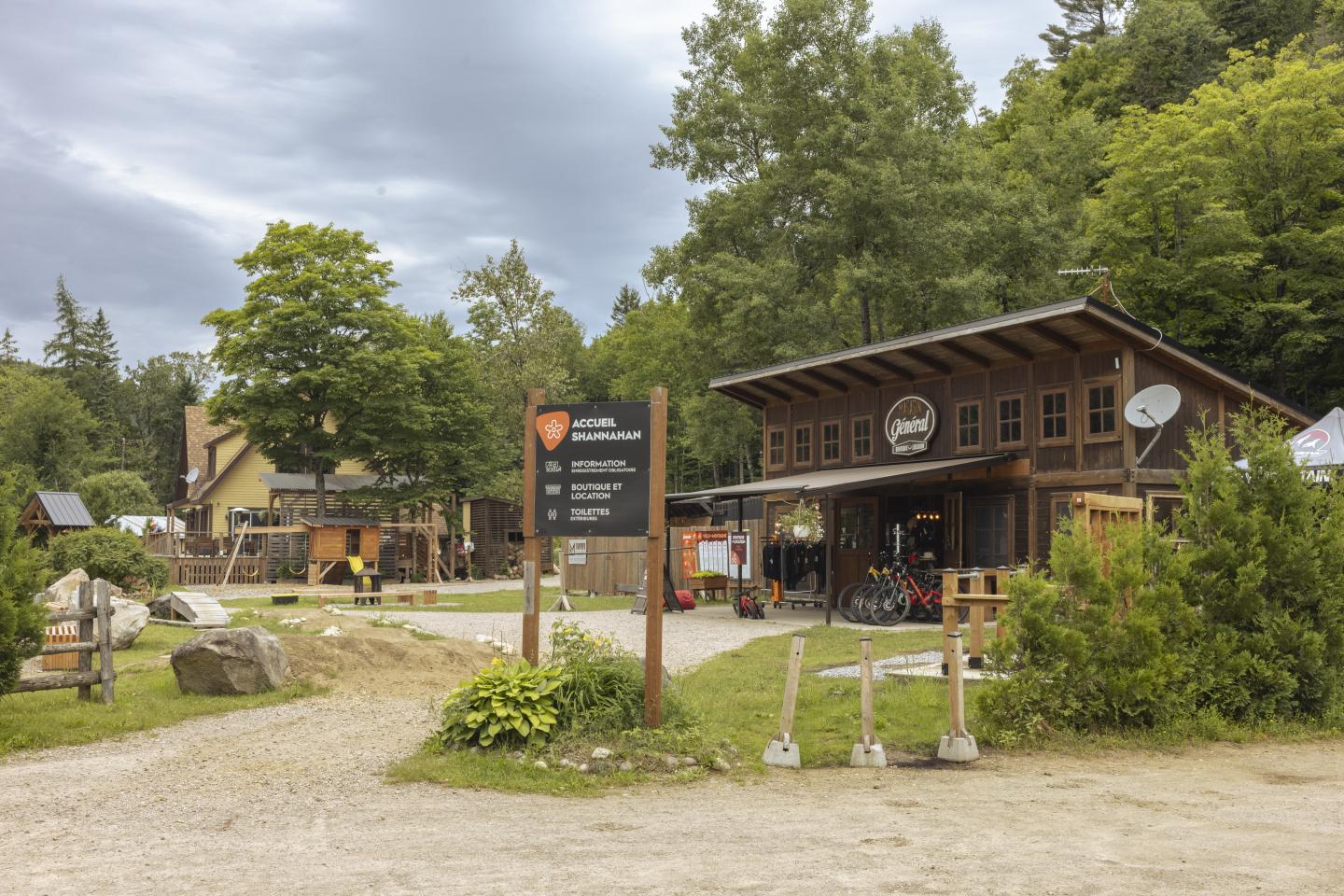 trée d'un centre de loisirs en bois entouré de verdure.