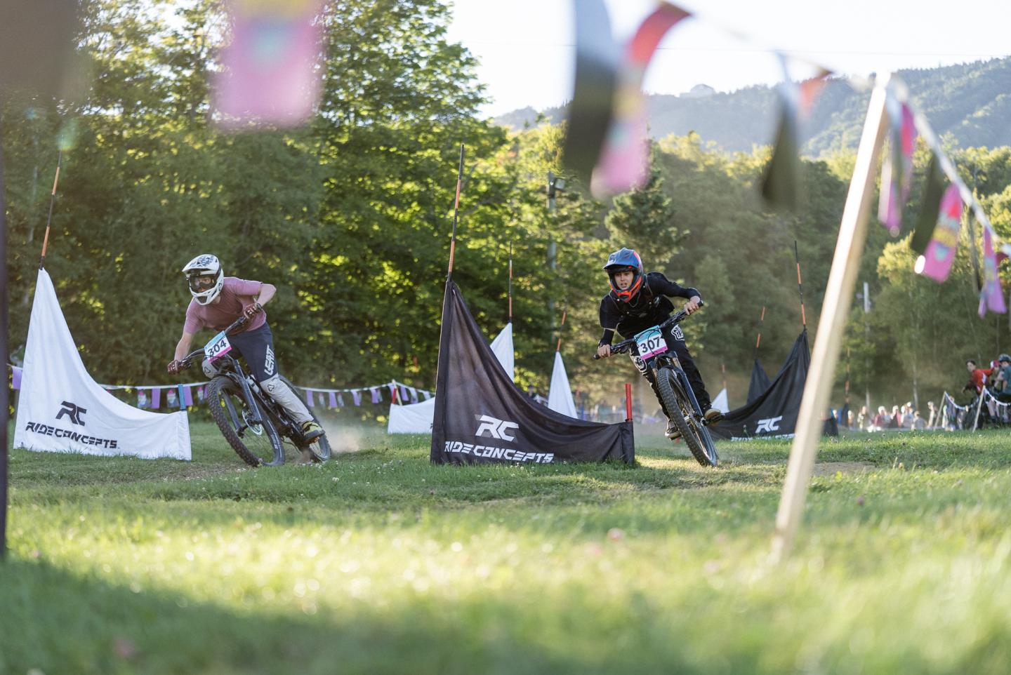 Cyclistes en course sur une pelouse, montagnes en arrière-plan.
