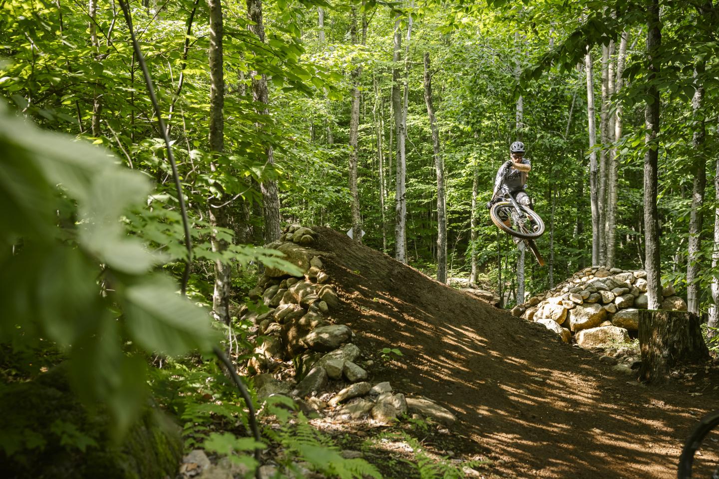 Cycliste sautant sur un sentier forestier en VTT.